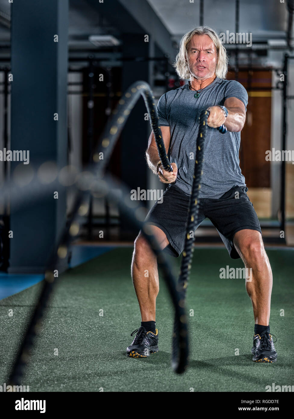 Athletic man exercising with bataille des cordes at gym Banque D'Images