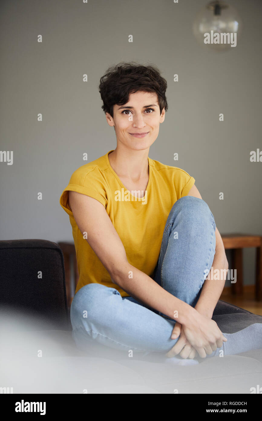 Portrait of smiling woman sitting on sofa at home Banque D'Images