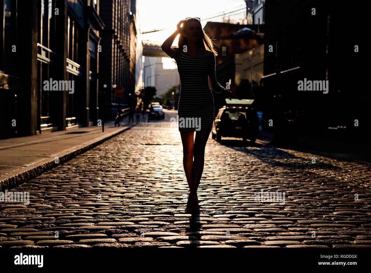 USA, New York, Brooklyn, Dumbo, silhouette of young woman standing on street à rétro-éclairage Banque D'Images