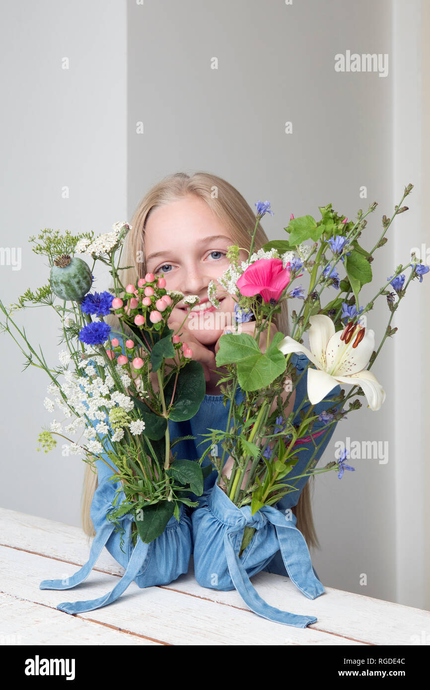Portrait of smiling blonde avec des bouquets de fleurs dans les manches de sa robe Banque D'Images