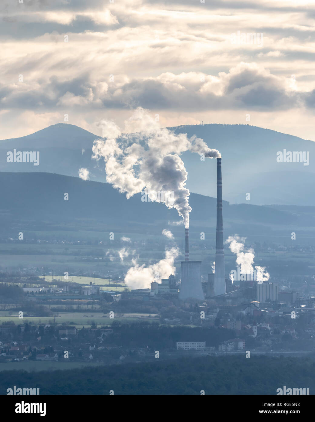 Usine en Slovaquie rétroéclairé avec de la fumée blanche provenant de cheminées en fin d'après-midi avec de hautes montagnes en arrière-plan Banque D'Images