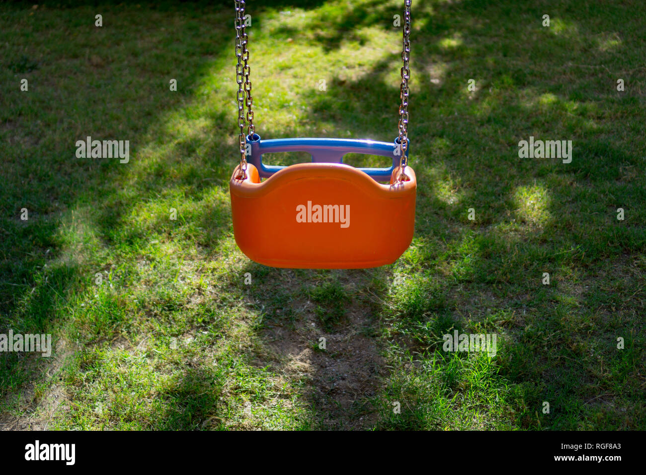 La chaîne Orange swing dans le jardin. L'été. Vue de derrière. Banque D'Images La chaîne Orange swing dans le jardin. L'été. Vue de derrière. Banque D'Images