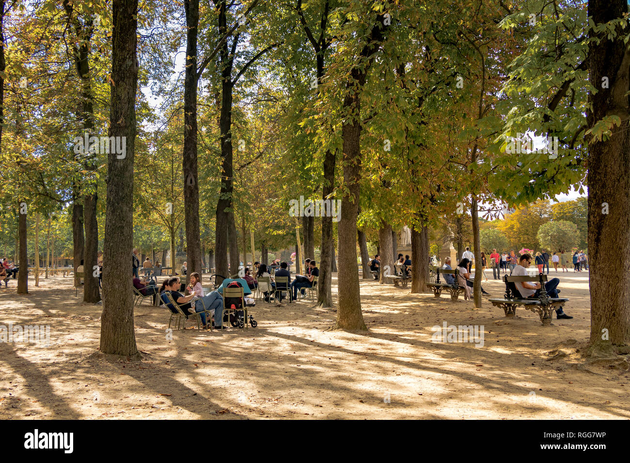 Des gens assis sur des bancs et des chaises à l'ombre des arbres sur une chaude journée d'été dans le Jardin du Luxembourg , Paris , France Banque D'Images