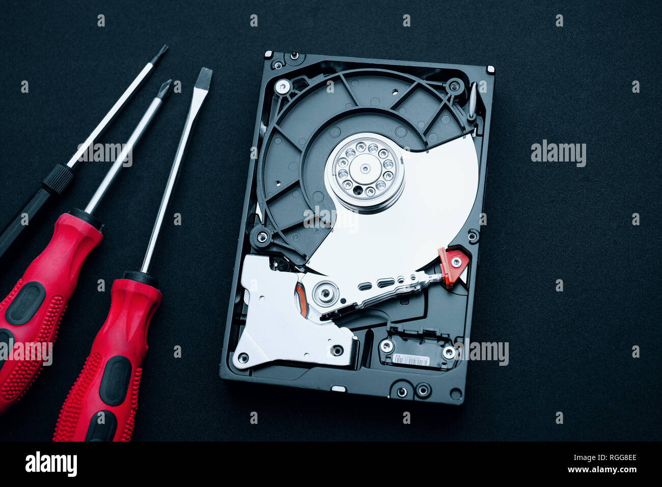 Vue de dessus du disque dur et de tournevis découvert sur le bureau. Assemblage du matériel à l'intérieur montrant des plateaux magnétiques et les disques de bras de lecture/écriture de l'actionneur. Banque D'Images