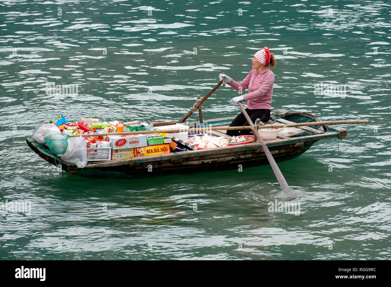 Femme vendant des produits à partir d'un bateau sur la baie d'Halong, Vietnam, Asie Banque D'Images