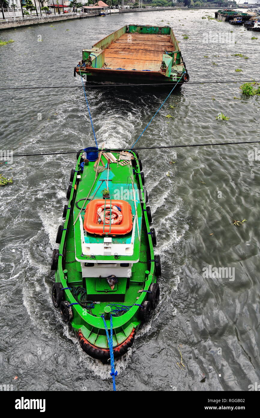 Remorqueur tractant une grande barge de cargaisons sèches en vrac avec soute vide sur la rivière Pasig à propos de passer sous le Willian A.Jones Memorial Bridge reliant Bino Banque D'Images