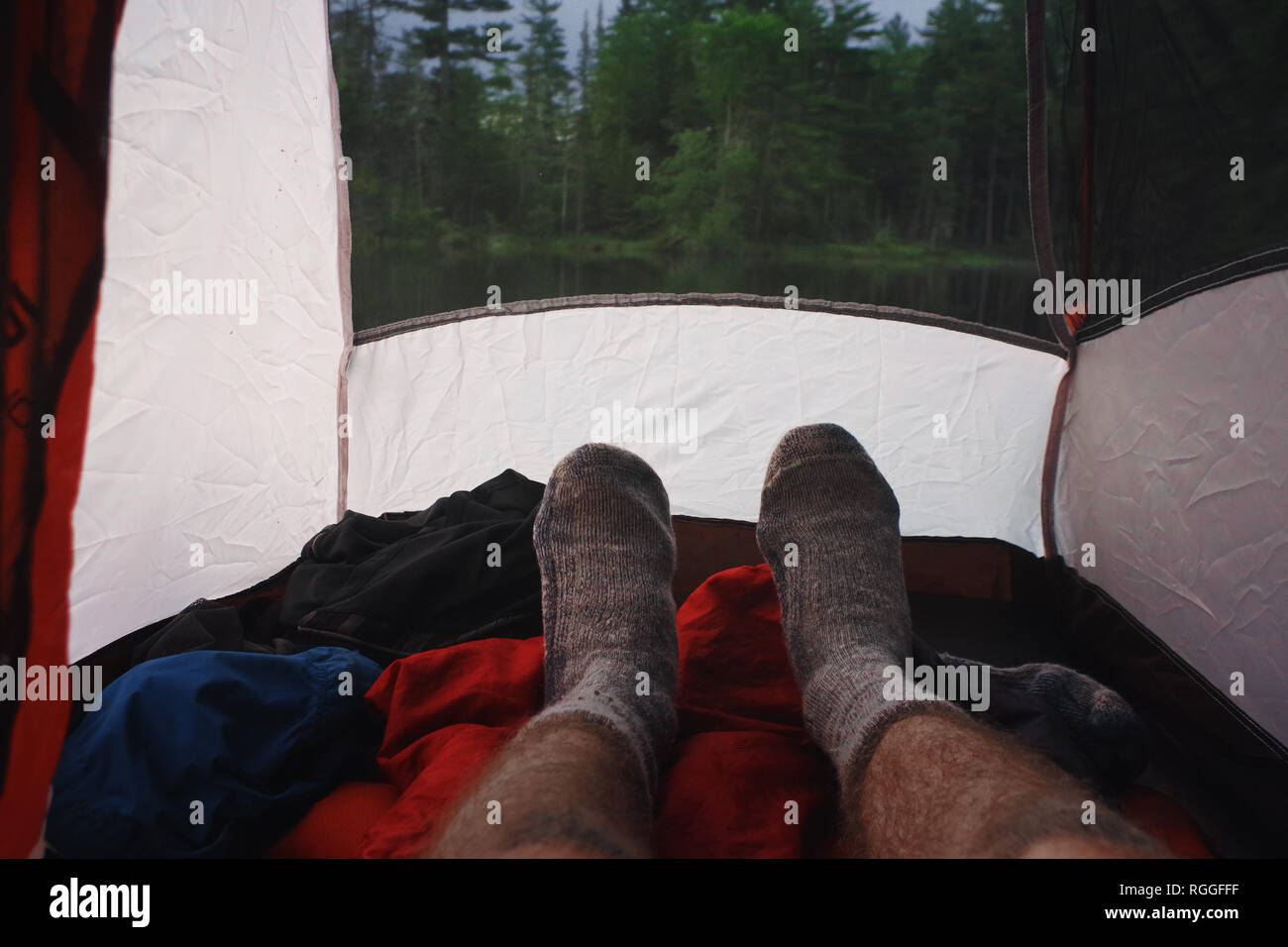 L'homme se détendre avec des bas de laine en camping dans une tente dans les montagnes Adirondack Banque D'Images