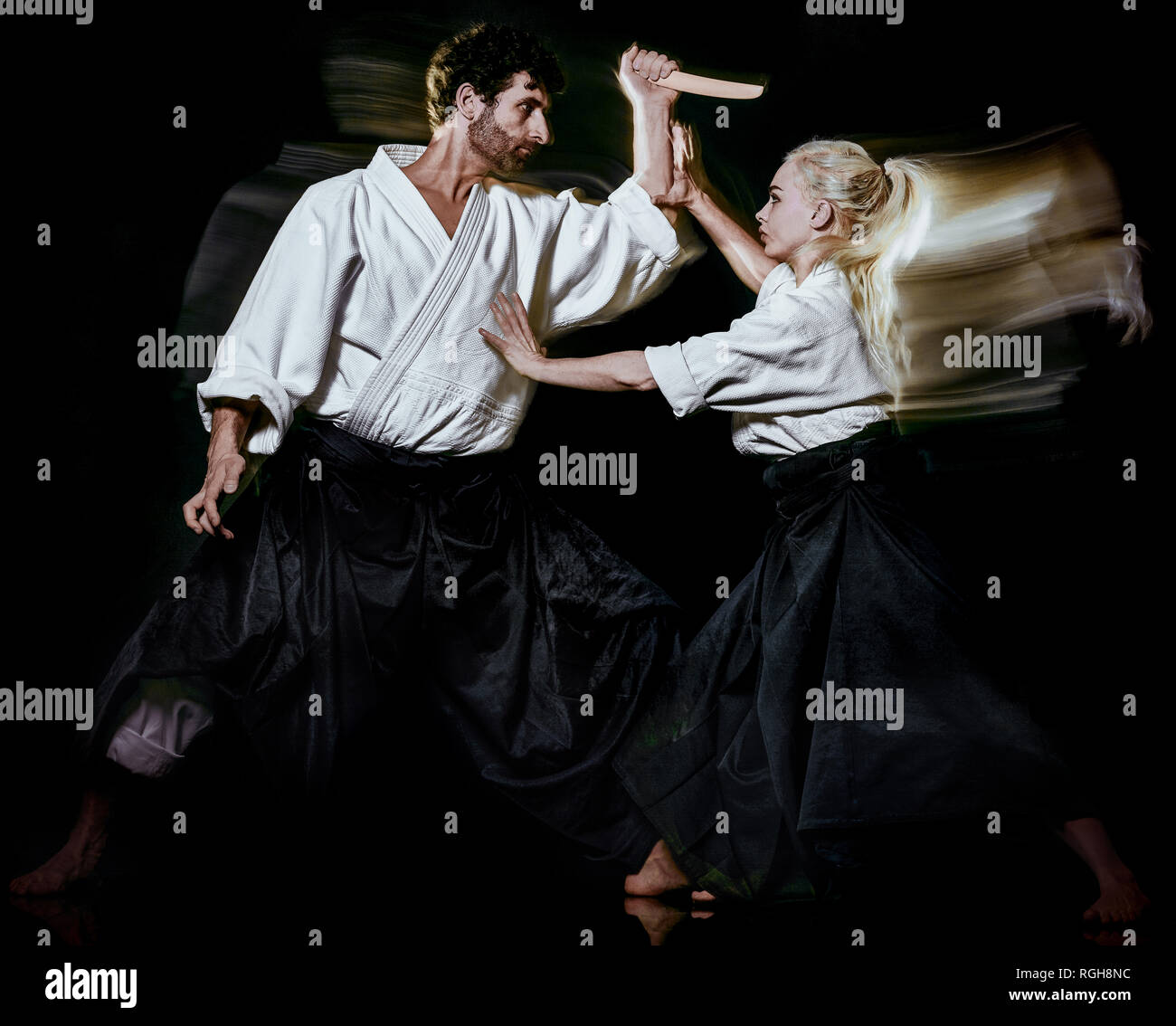 Deux budokas fighters l'homme et la femme l'Aikido studio shot isolé sur fond noir Banque D'Images