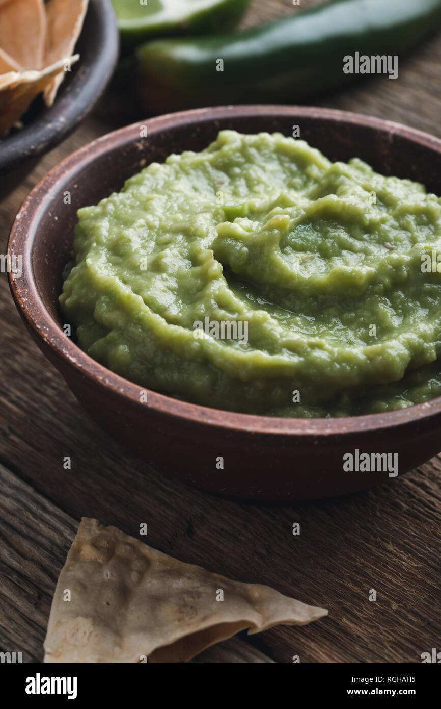 Dip guacamole frais avec le jus de lime dans un bol en céramique sur table rustique en bois, style mexicain traditionnel, sauce à l'avocat, snack-végétalienne saine Banque D'Images