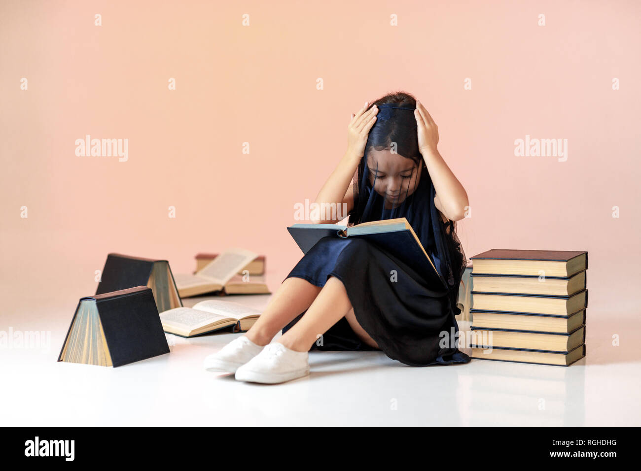 Cute little girl est en train de lire un livre. Banque D'Images