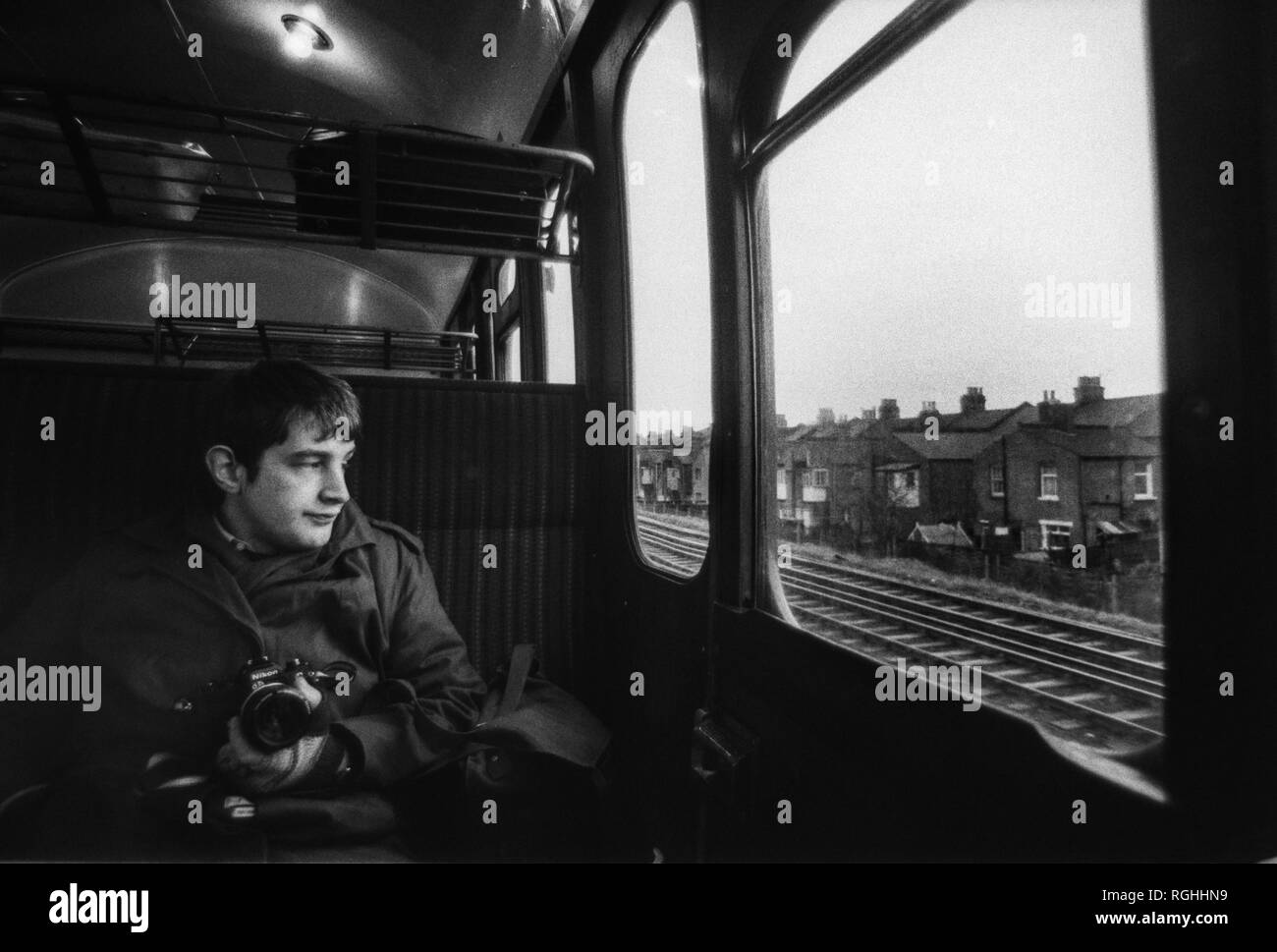 Image d'archive d'un photographe avec appareil photo reflex Nikon à la recherche par la fenêtre d'un British Rail train dans une porte claquer les faubourgs du sud de Londres, 1979, Londres, Angleterre Banque D'Images