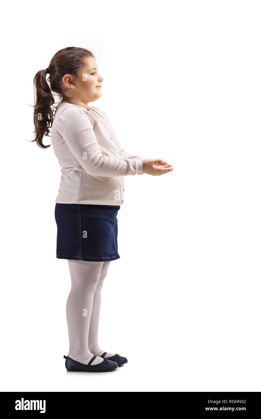 Profil de pleine longueur tourné d'une petite fille faisant des gestes avec ses mains et attendre de recevoir quelque chose d'isolé sur fond blanc Banque D'Images