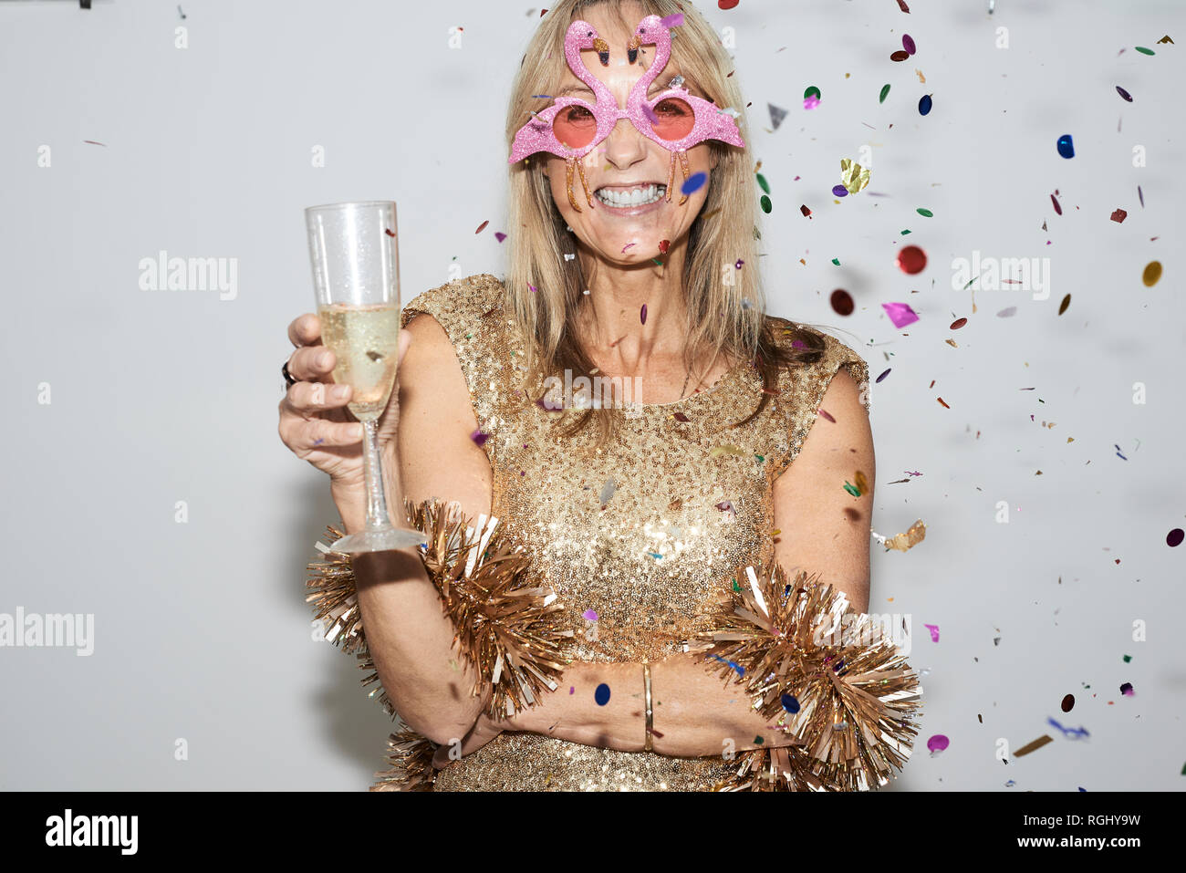 Senior woman wearing robe d'or et en forme de lunettes, celebtraing flmingo New Year's Eve Banque D'Images