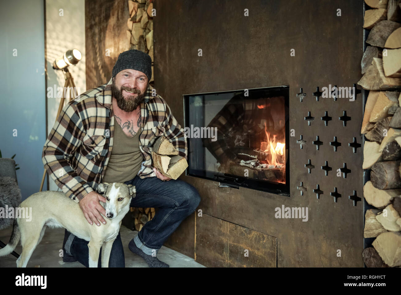Portrait of smiling man avec son chien devant le foyer à la maison Banque D'Images