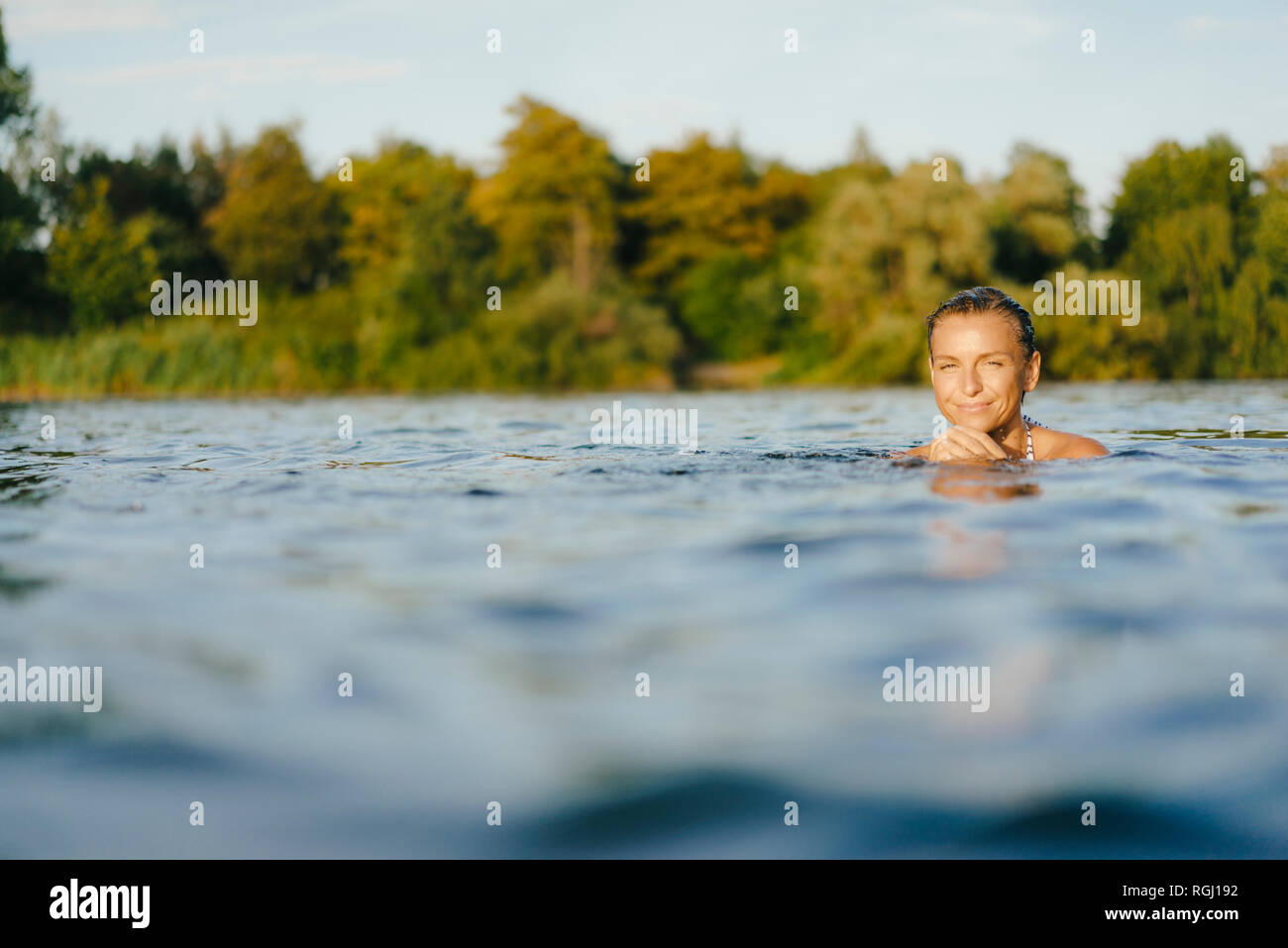 Portrait of smiling woman swimming in a lake Banque D'Images