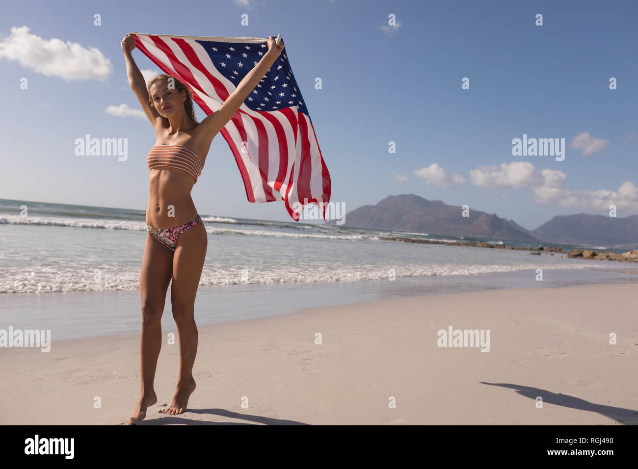 Woman waving American flag at beach Banque D'Images