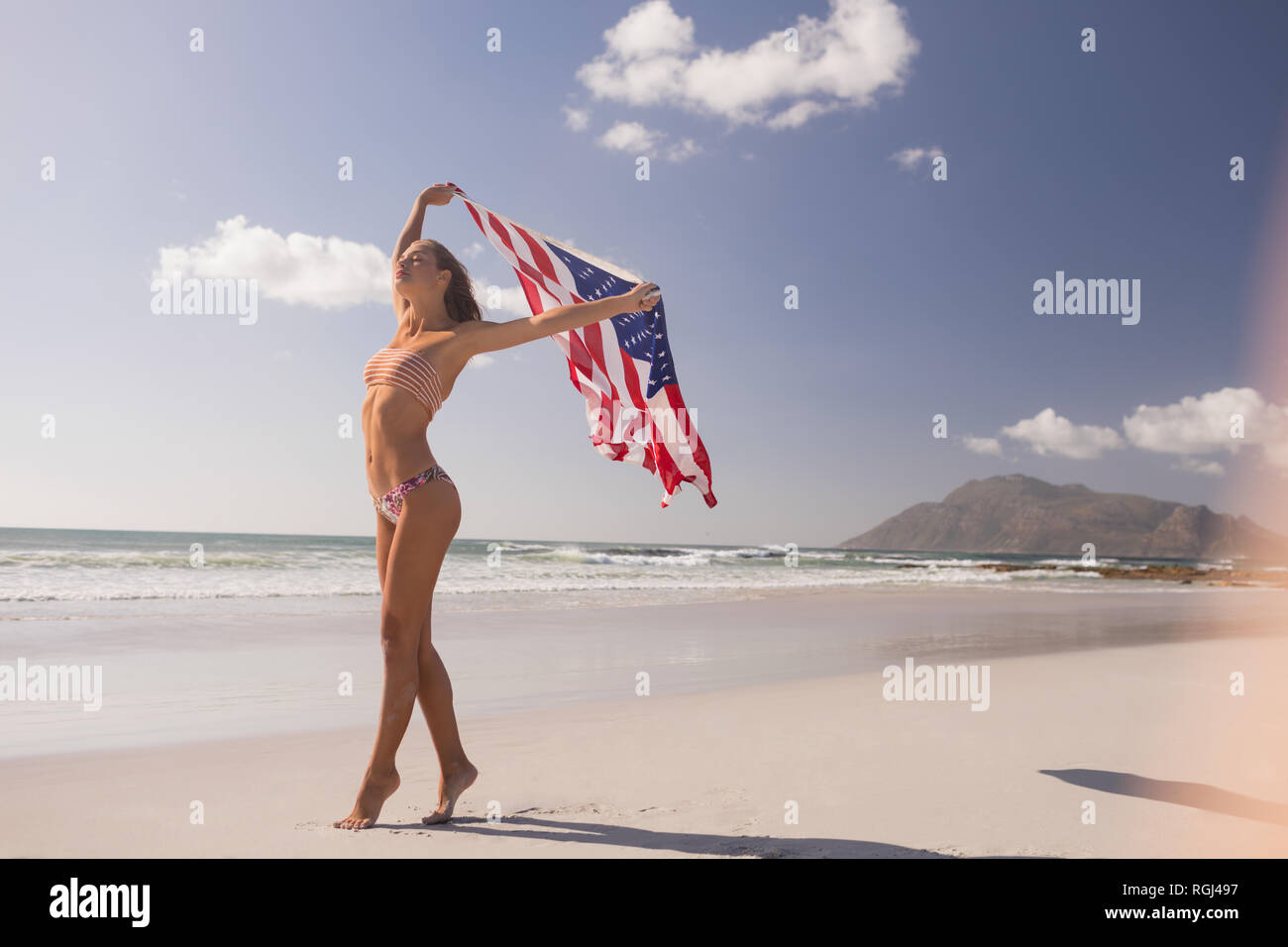 Woman waving American flag at beach Banque D'Images