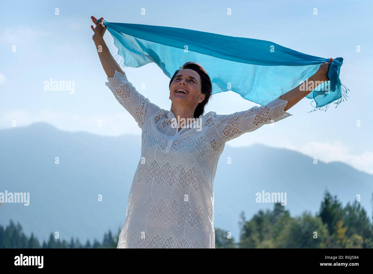 Happy woman holding se balancer à l'écharpe bleue, au bord de la Haute-Bavière, Allemagne Banque D'Images