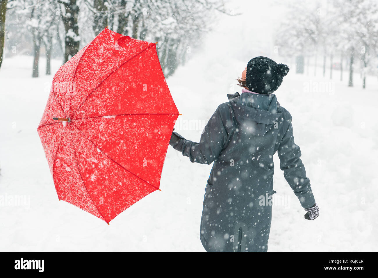 Heureux femme avec parapluie rouge bénéficiant d'hiver neige à l'extérieur dans le parc Banque D'Images
