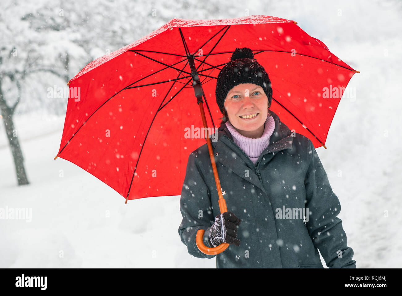 Heureux femme avec parapluie rouge bénéficiant d'hiver neige à l'extérieur dans le parc Banque D'Images
