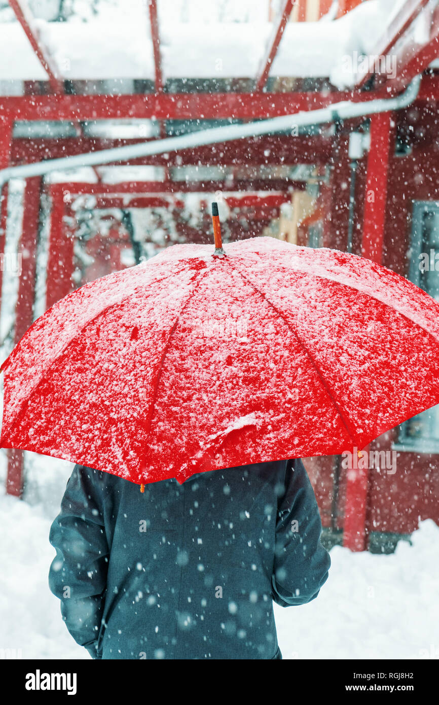 Triste et seule femme parapluie rouge sous la neige en hiver grâce à l'environnement urbain Banque D'Images