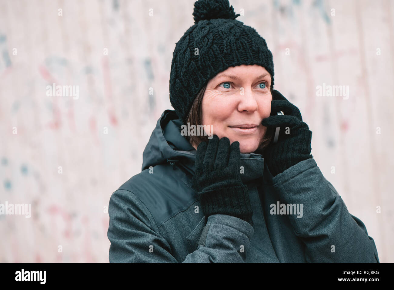 Mobile phone conversation, des profils caucasian Woman talking on smartphone dans la rue par une froide journée d'hiver Banque D'Images