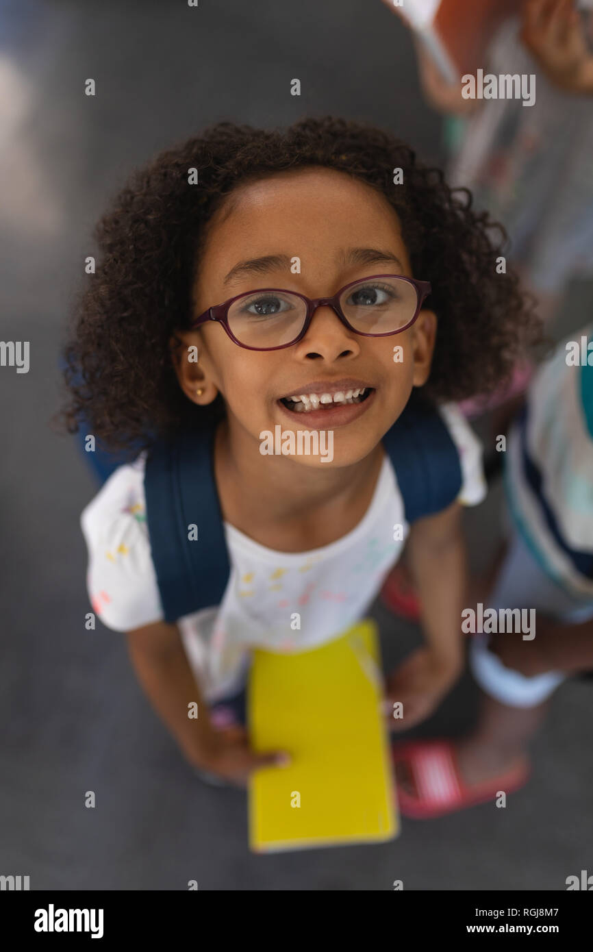 High angle view of happy écolière avec sac looking at camera in classroom Banque D'Images