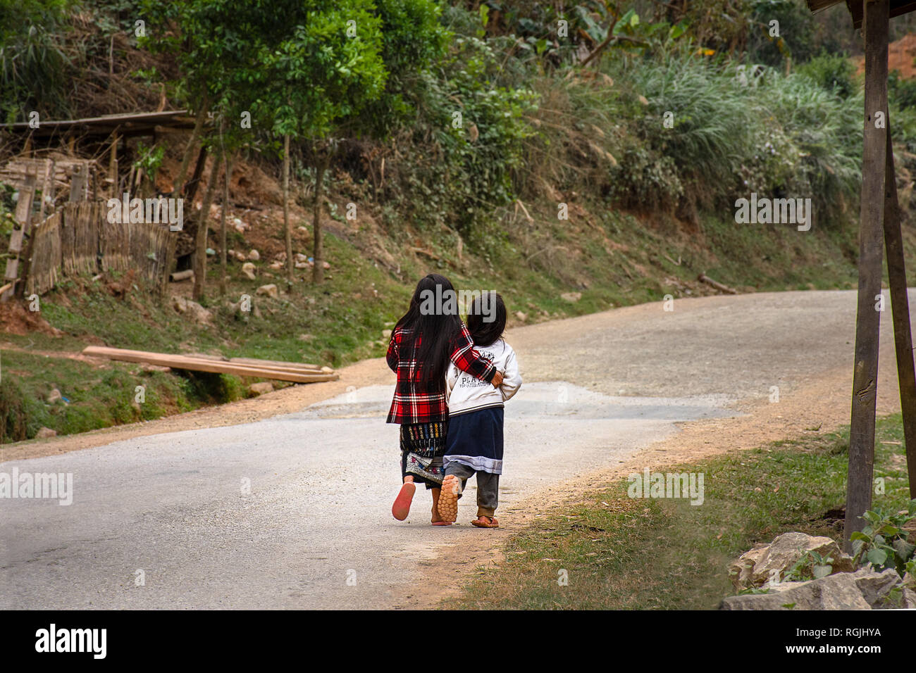 Deux jeunes filles vietnamiennes à pied le long d'une rue rurale edge avec amour. Banque D'Images