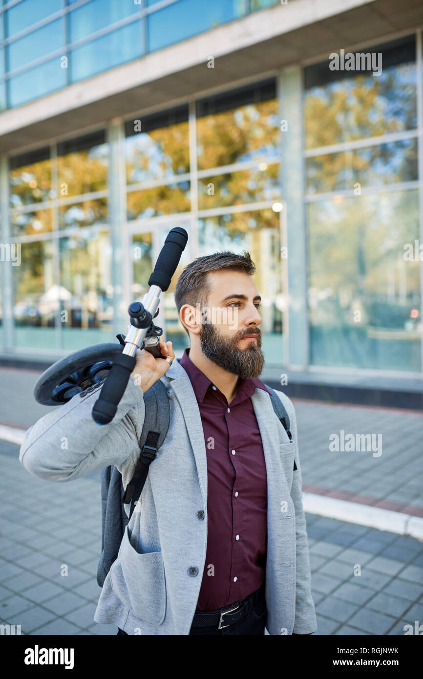 Businessman carrying scooter Banque D'Images