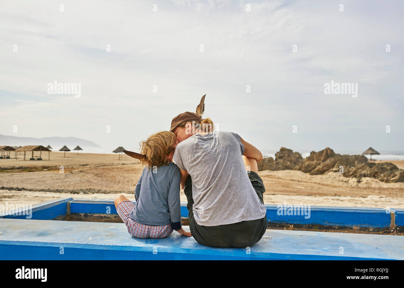 Le Chili, Arica, mère assise avec fils sur mur sur la plage Banque D'Images