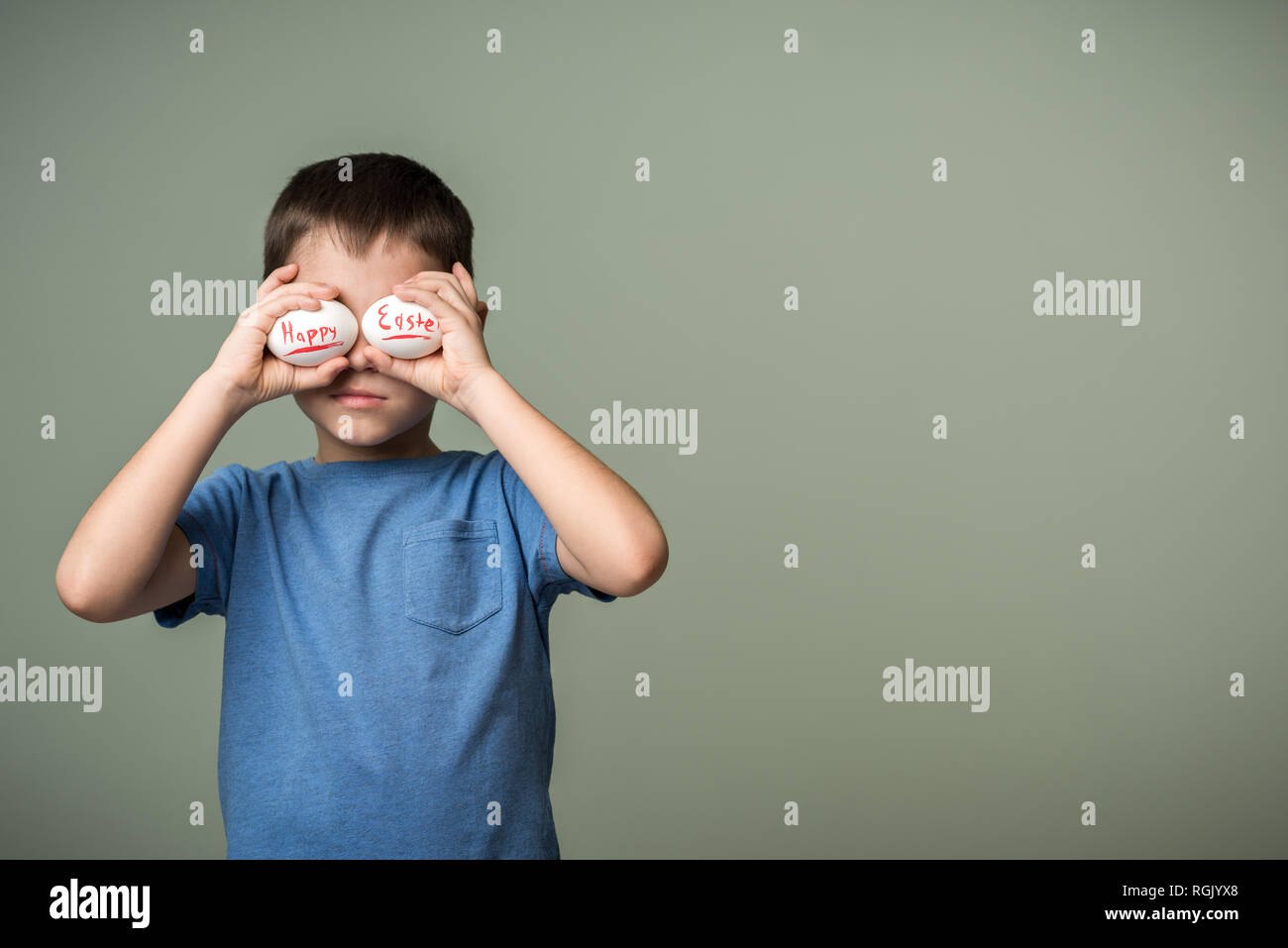 Les œufs avec l'inscription Joyeuses Pâques dans les mains d'un enfant. Fond vert. Idées de Pâques. L'espace pour le texte. Les oeufs de Pâques. Lettrage de corail vivant. H Banque D'Images