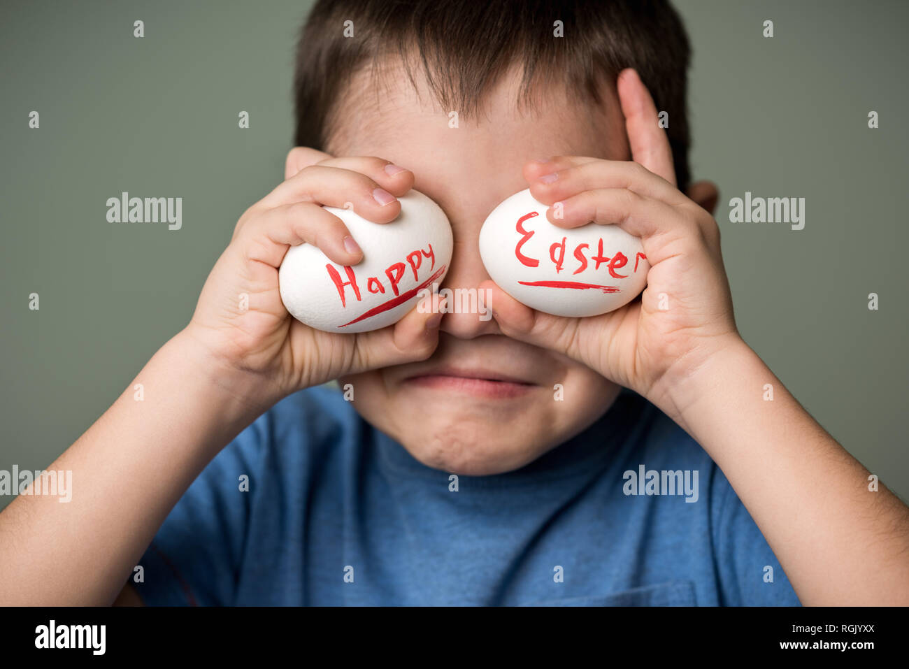 Les œufs avec l'inscription Joyeuses Pâques dans les mains d'un enfant. Fond vert. Idées de Pâques. L'espace pour le texte. Les oeufs de Pâques. Lettrage de corail vivant. H Banque D'Images