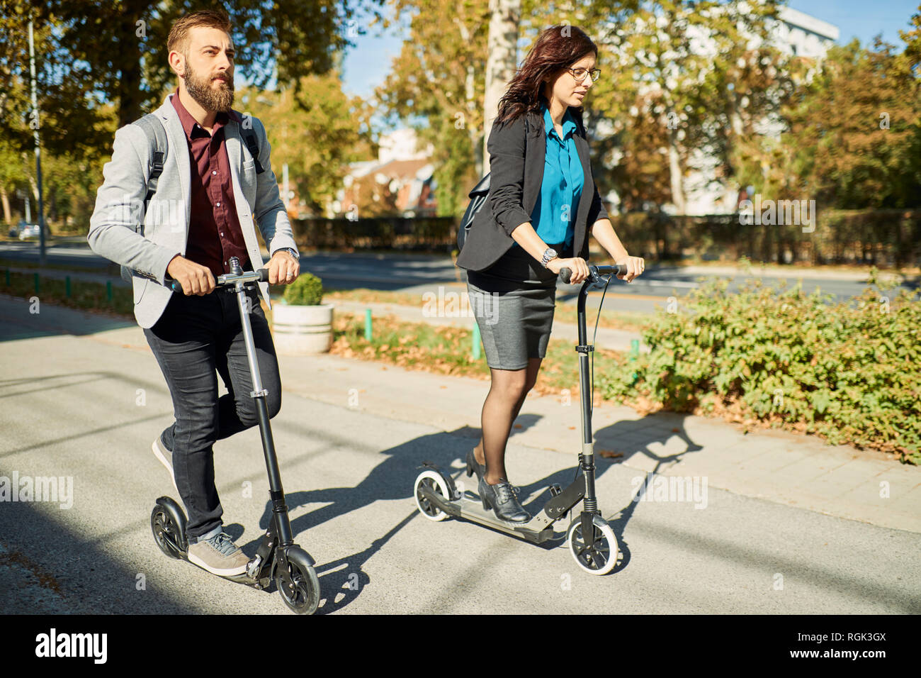 Businessman and businesswoman riding scooter Banque D'Images