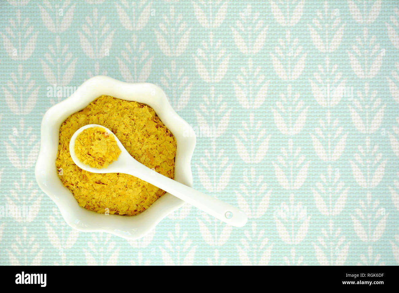 La levure alimentaire en flocons blanc cannelé bol et cuillère sur fond texturé turquoise pâle tourné à partir de ci-dessus. Format horizontal avec place pour le texte. Banque D'Images
