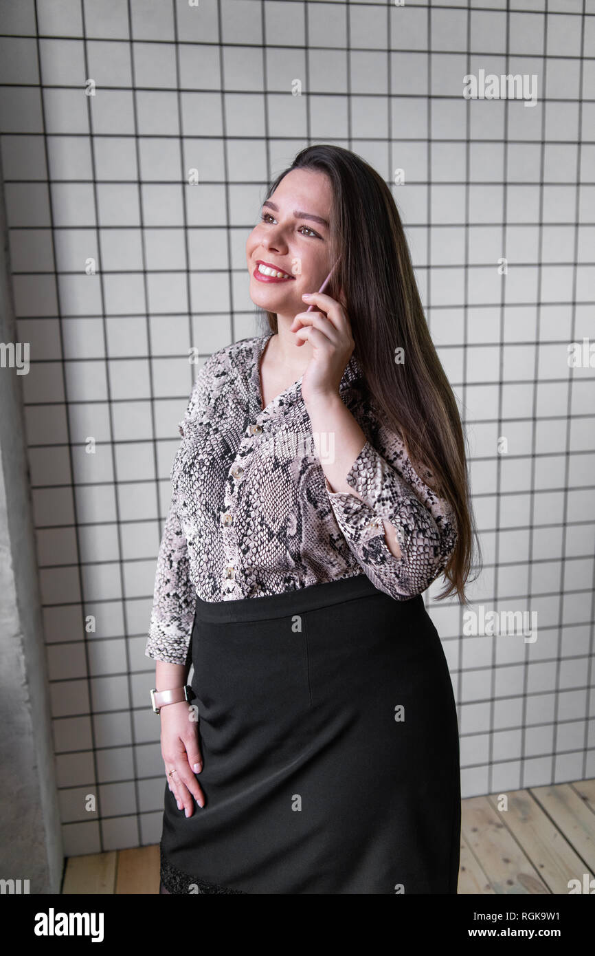Close up Young Office femme parlant à quelqu'un sur son téléphone portable tout en regardant dans la distance avec l'expression du visage heureux Banque D'Images