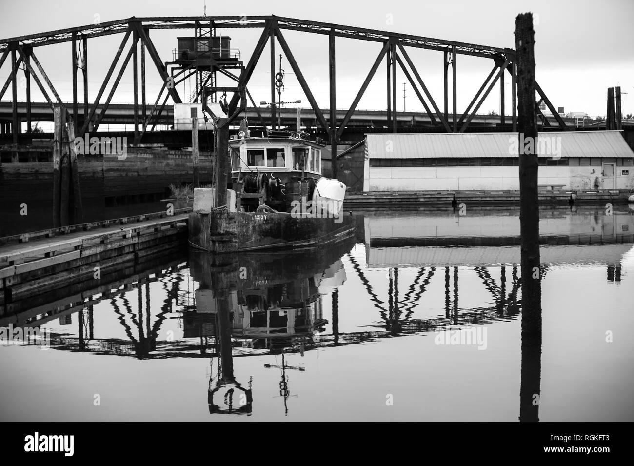Vieux remorqueur abandonné dans la marina industrielle avec trèfle de train en arrière-plan Banque D'Images