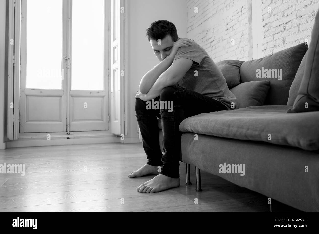 Déprimé malheureux homme de race blanche assise, je pleurais et couché dans canapé du salon un sentiment de solitude désespérée en souligné de travail, le chômage, l'Anxiété Banque D'Images