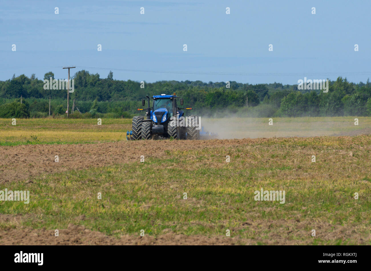 Vue avant du tracteur laboure le terrain avec une herse de fer dans la saison de labour avec la poussière tourbillonnante Banque D'Images