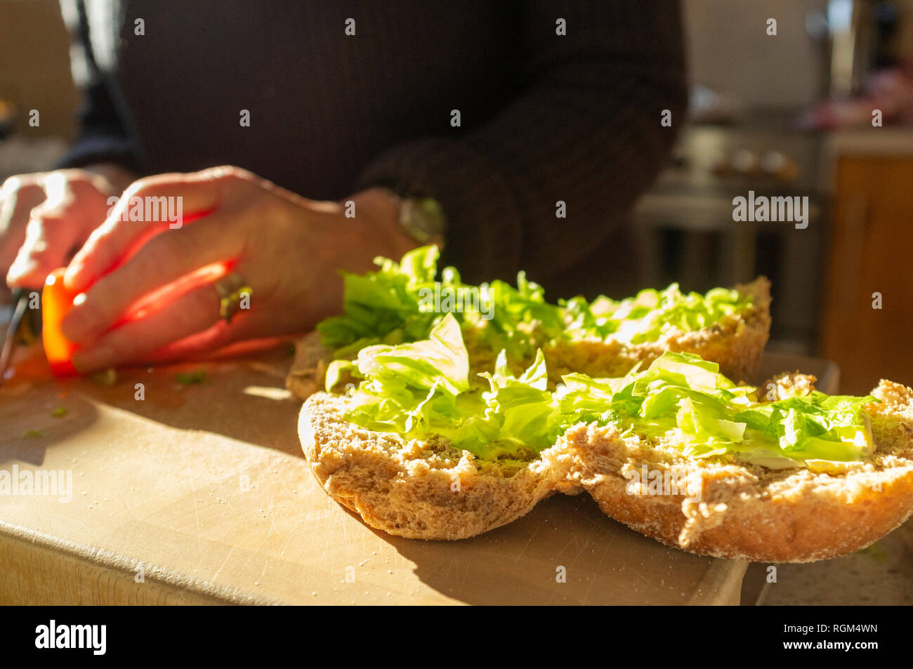 Femme porte rouleaux sandwich dans la cuisine tandis que les rayons du soleil à travers la fenêtre Banque D'Images