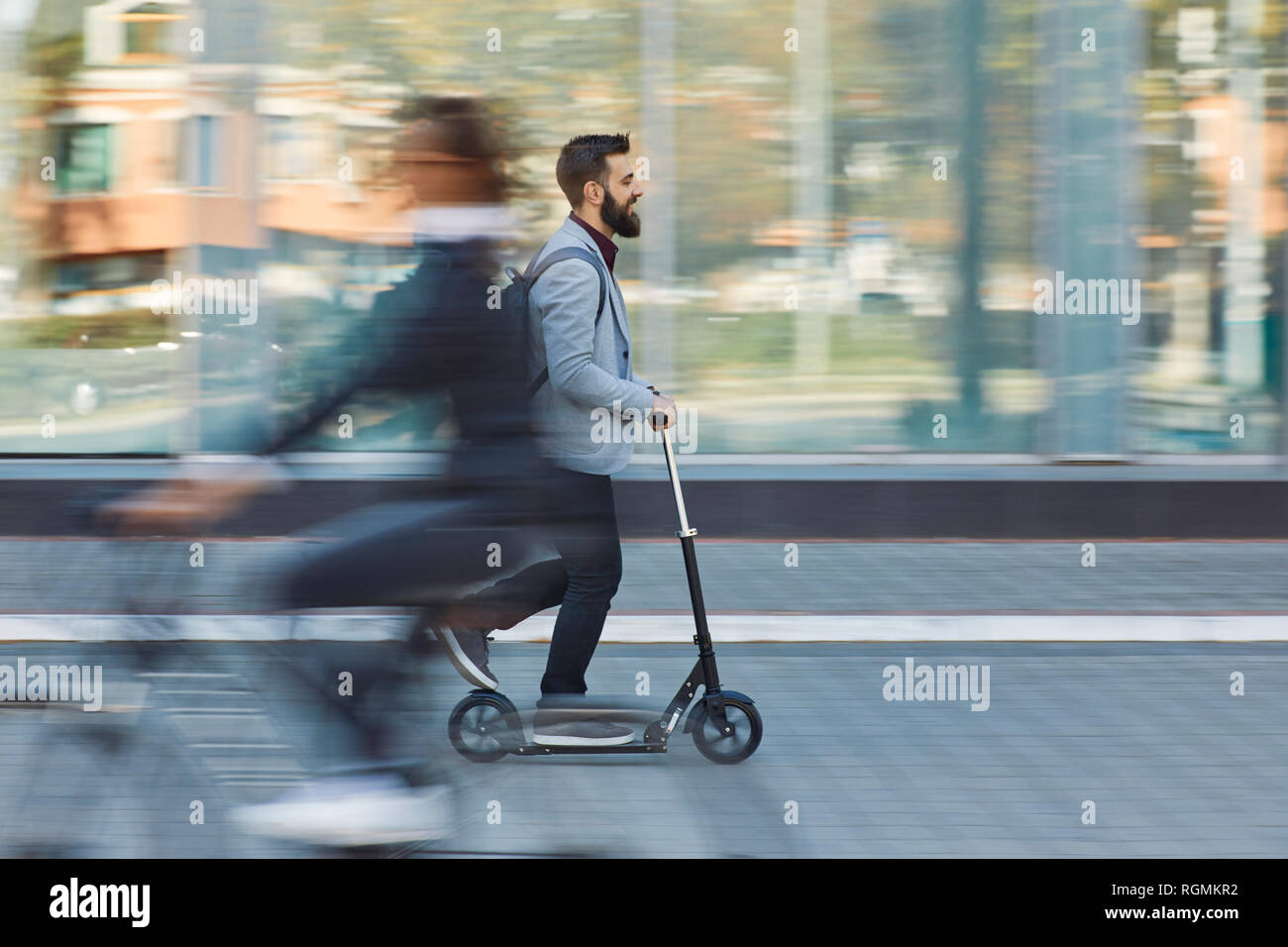 Businessman riding scooter le long office building Banque D'Images