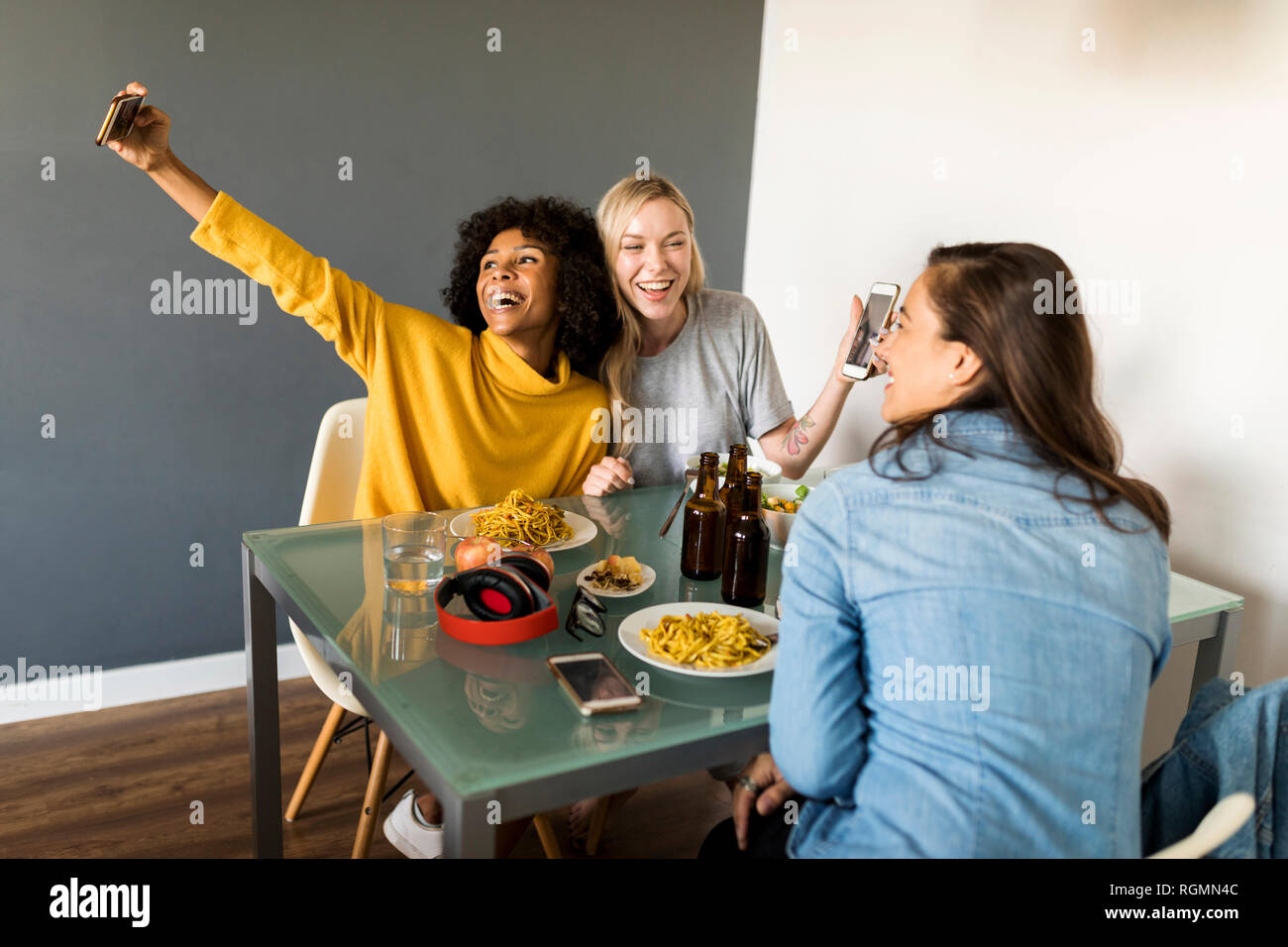Copines heureux assis à table à manger en tenant un selfies Banque D'Images