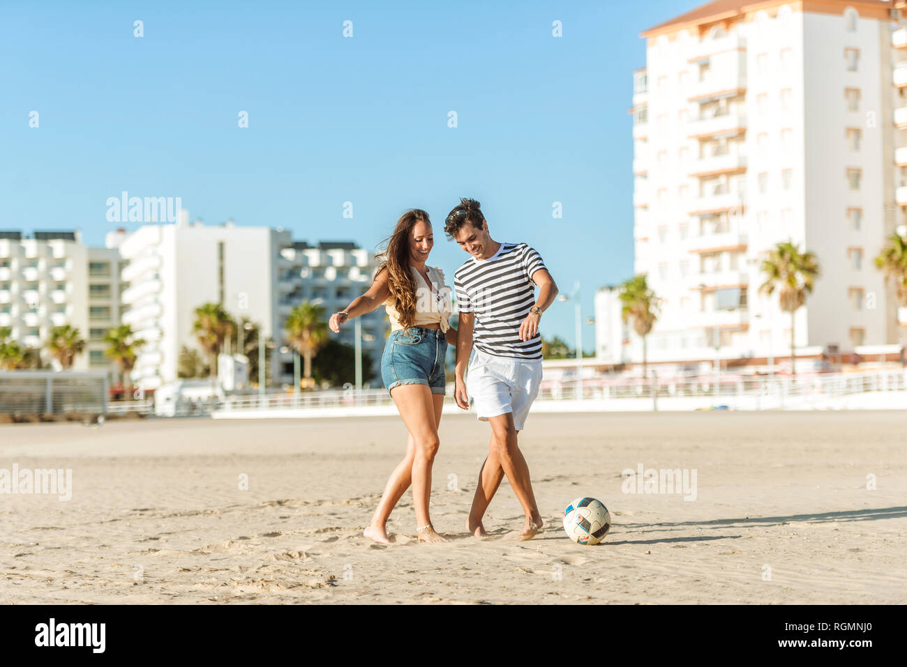 Happy young couple jouant au football sur la plage Banque D'Images