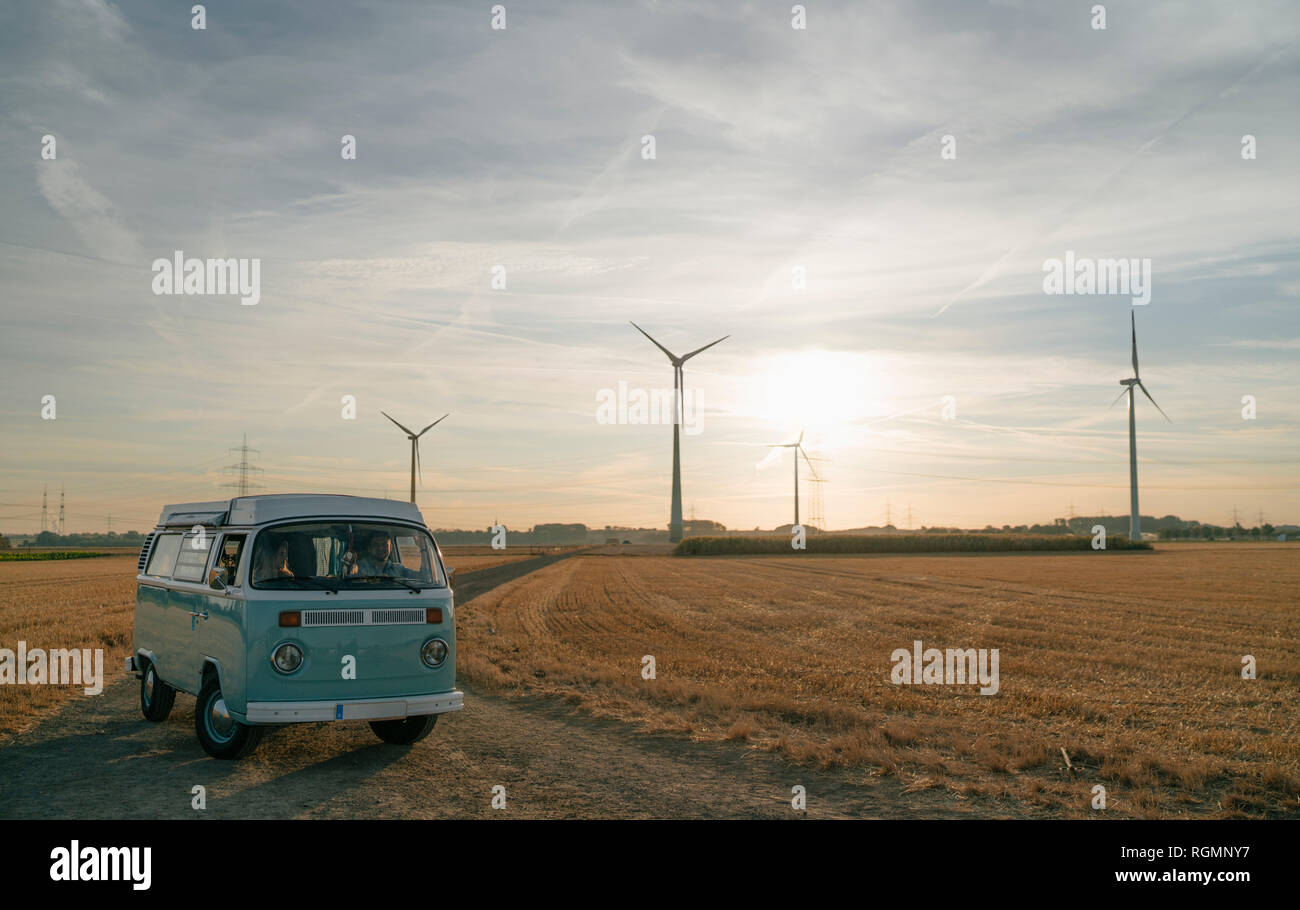 Couple dans le camping-car en milieu rural paysage avec éoliennes au coucher du soleil Banque D'Images