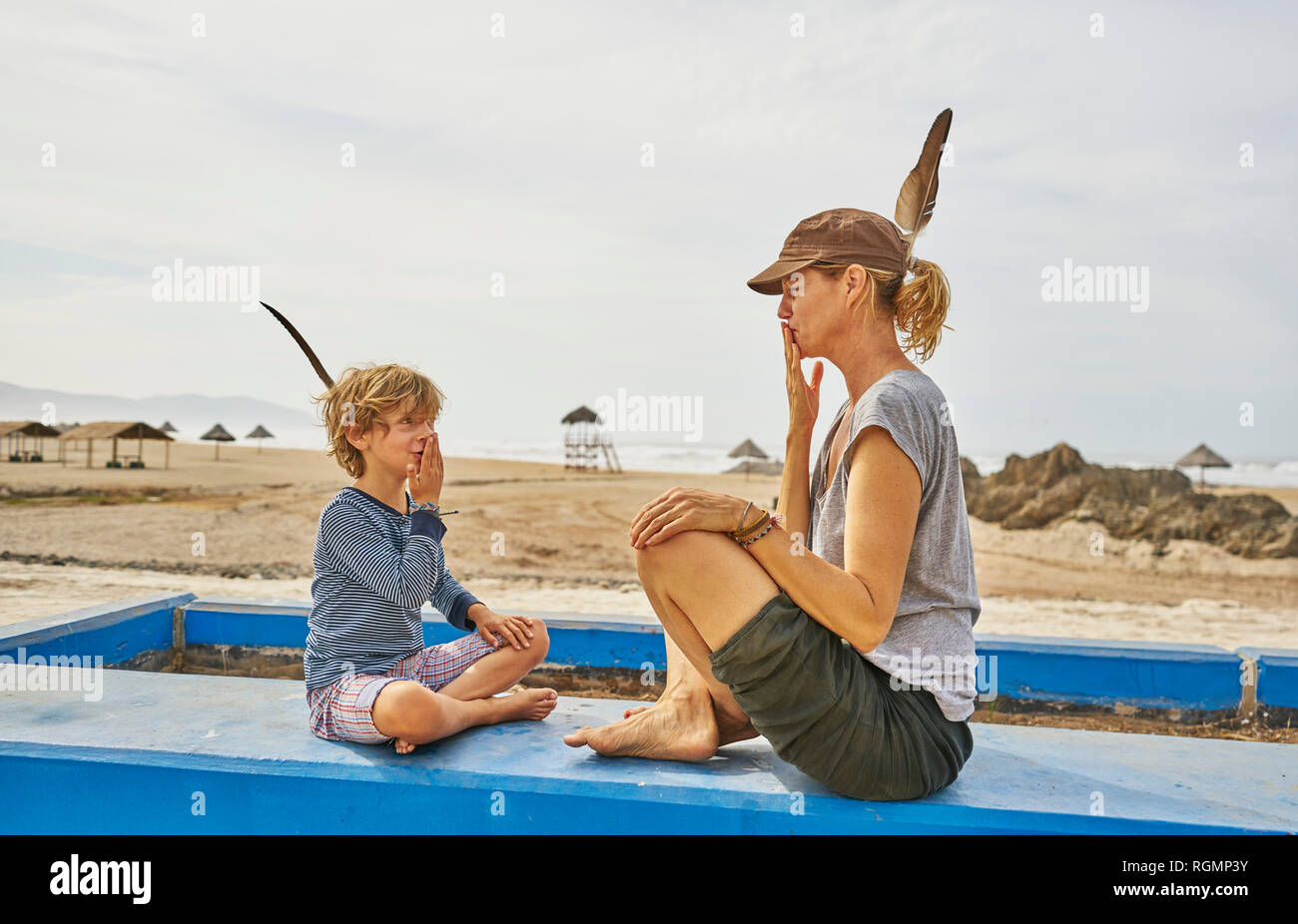 Le Chili, Arica, mère assise avec fils sur mur sur la plage Banque D'Images