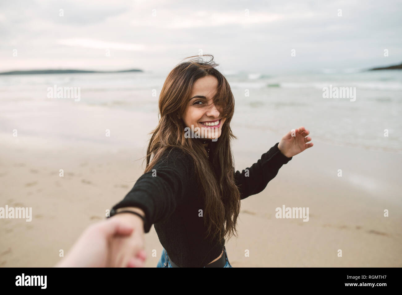 Portrait of smiling young woman holding hands on the beach Banque D'Images