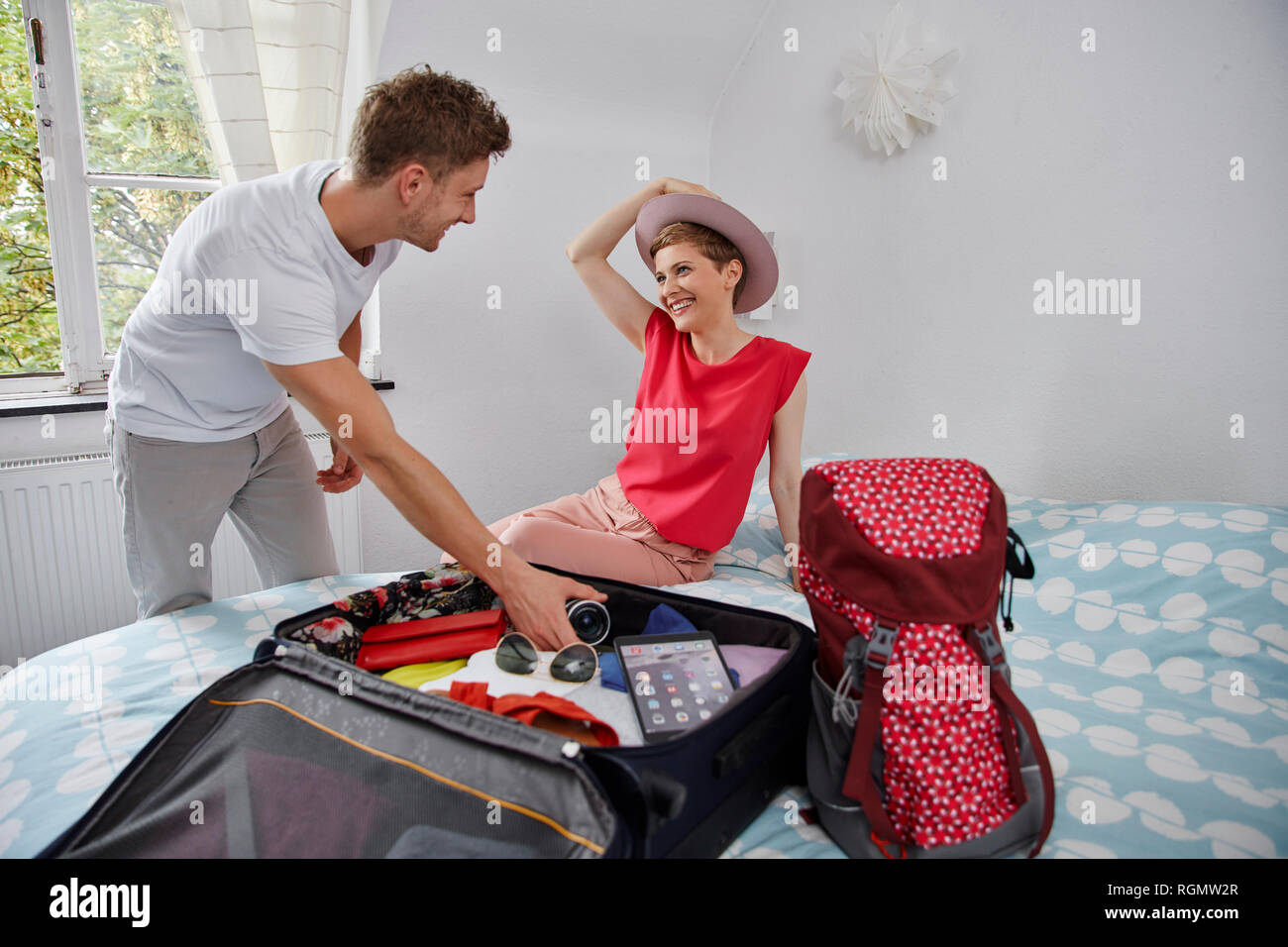Heureux couple packing valise pour les vacances d'été on bed Banque D'Images