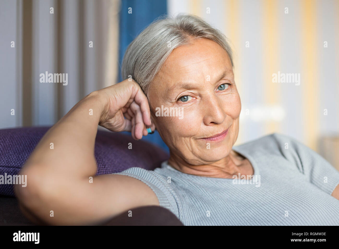 Portrait of smiling senior woman relaxing sur le canapé à la maison Banque D'Images