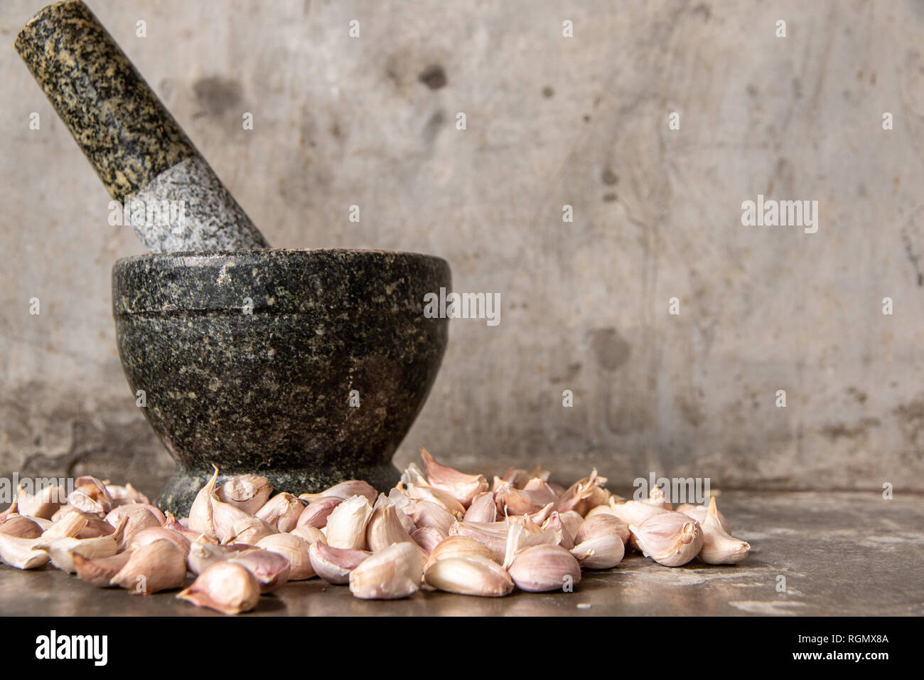 L'ail avec mortier de pierre sur le dessus de table en ciment. Banque D'Images