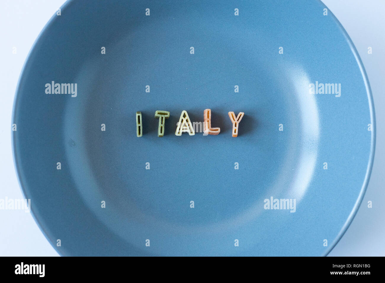 Le mot 'Italie' composé avec du vrai pâtes lettres dans le pavillon italien des couleurs dans un plat bleu. Banque D'Images