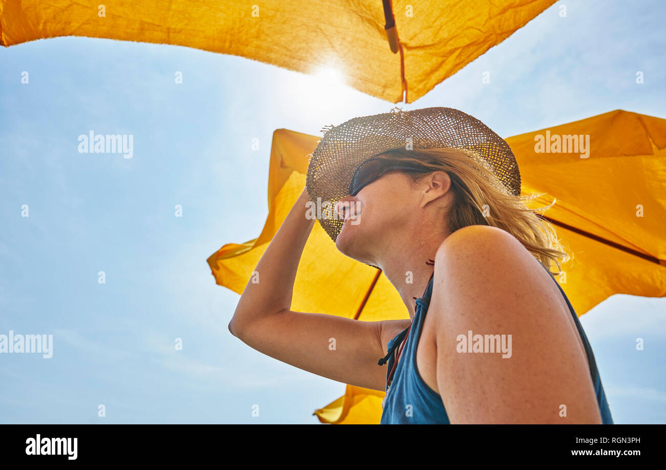 Smiling woman wearing straw hat dans sunsahde in sunlight Banque D'Images